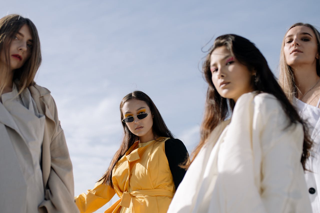 Fashionable women posing confidently in chic outfits under the clear sky.